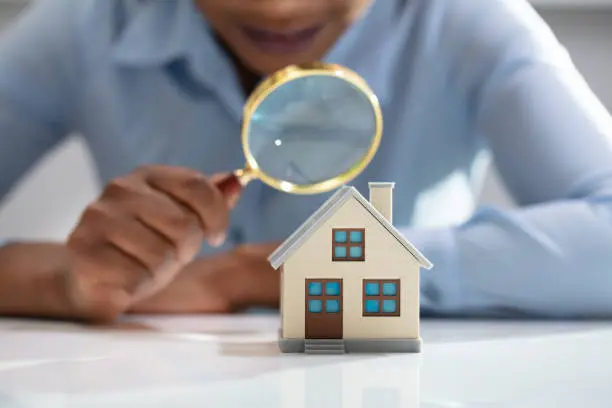 A person looking at a house through a magnifying glass