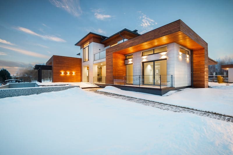 A large modern house with snow on the ground.